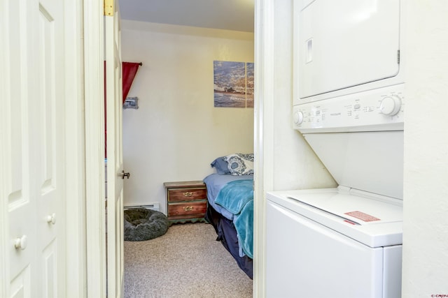 clothes washing area featuring laundry area, carpet floors, baseboard heating, and stacked washer and clothes dryer