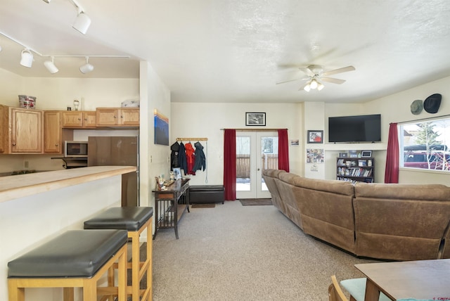 living room featuring light carpet, french doors, plenty of natural light, and a ceiling fan