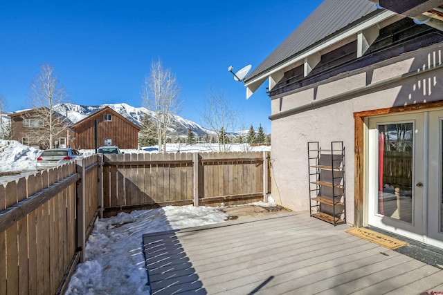 snow covered deck with a fenced backyard and a mountain view