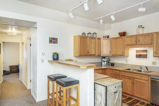 kitchen with tile countertops, a peninsula, a breakfast bar, a sink, and dishwasher