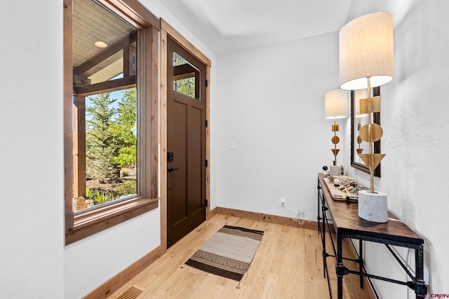 entryway with light wood finished floors, visible vents, and baseboards