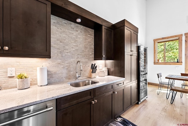 kitchen with a sink, backsplash, stainless steel dishwasher, and dark brown cabinets