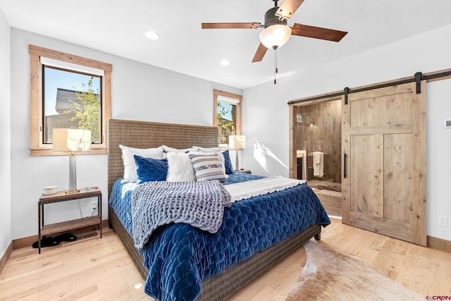 bedroom with wood finished floors, multiple windows, and a barn door