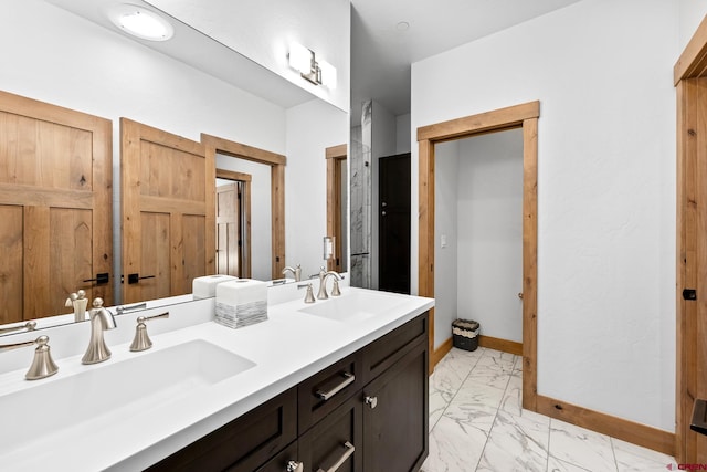 bathroom with double vanity, marble finish floor, baseboards, and a sink