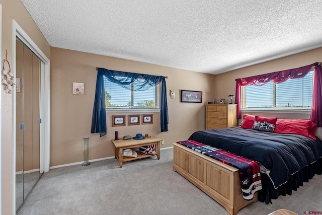 bedroom with light carpet, a textured ceiling, and baseboards