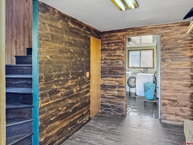 corridor with stairway, wood walls, and independent washer and dryer