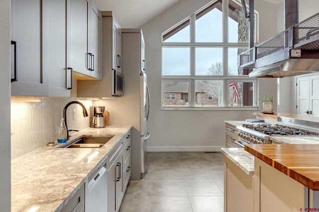 kitchen with light tile patterned floors, tasteful backsplash, baseboards, stainless steel appliances, and a sink