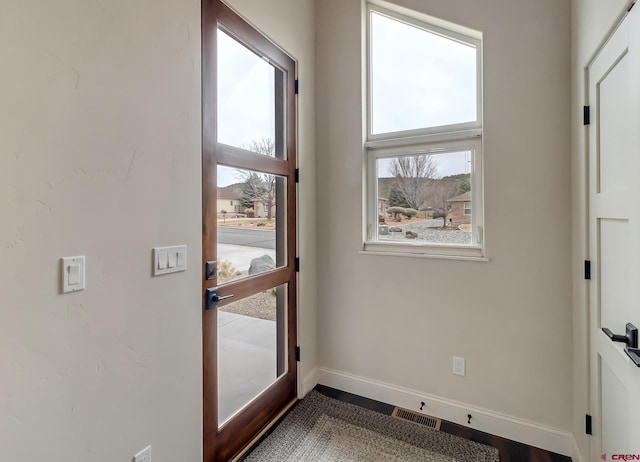 doorway to outside featuring a healthy amount of sunlight, baseboards, and visible vents