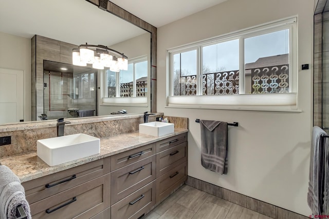 bathroom featuring double vanity, an inviting chandelier, a sink, and a shower stall