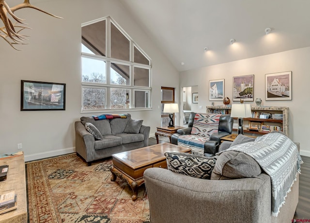 living area featuring high vaulted ceiling and baseboards