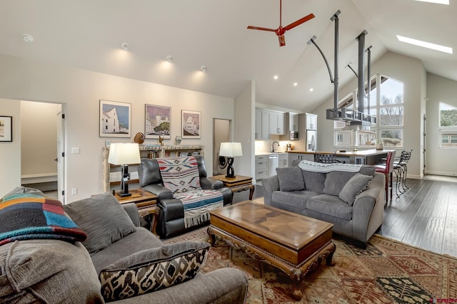 living room with high vaulted ceiling, a skylight, wood finished floors, a ceiling fan, and baseboards