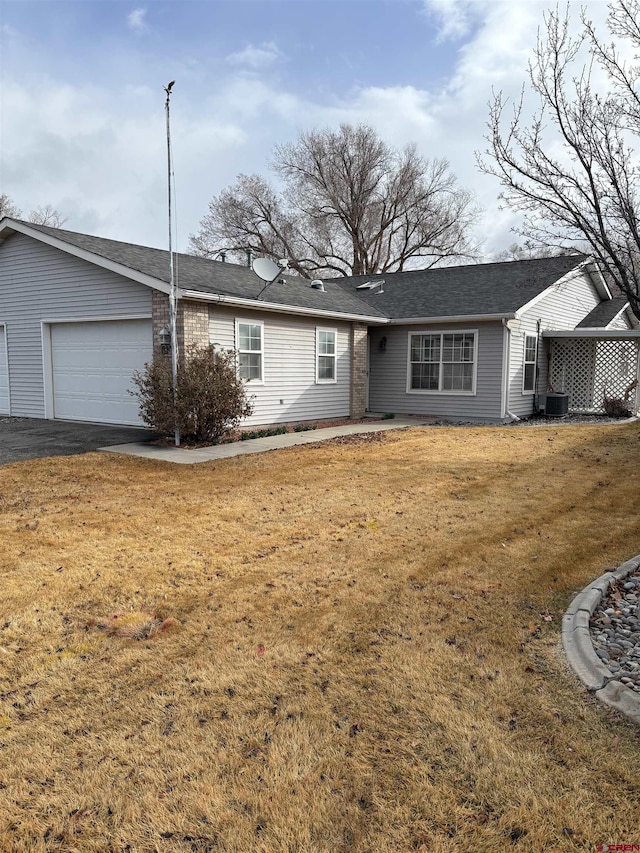 ranch-style home with a front lawn, an attached garage, and aphalt driveway