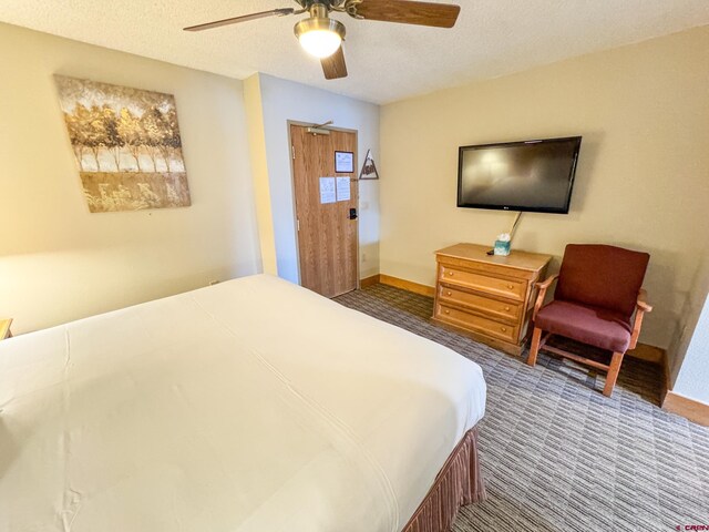 bedroom with a textured ceiling, carpet floors, ceiling fan, and baseboards