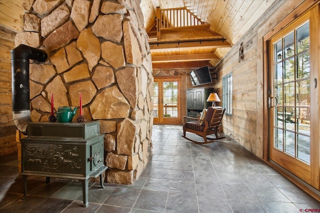 unfurnished room featuring wood ceiling, a wood stove, vaulted ceiling with beams, and french doors