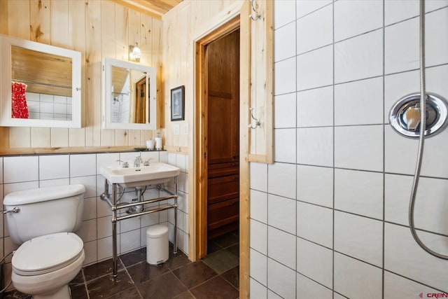 bathroom featuring a sink, tile patterned floors, toilet, and tile walls