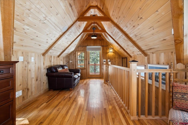 bonus room featuring lofted ceiling with beams, light wood finished floors, wood ceiling, and wood walls