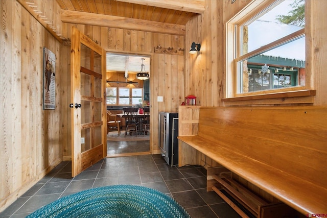 interior space with wood ceiling, wooden walls, beam ceiling, and dark tile patterned flooring