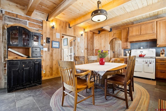 dining area featuring arched walkways, beamed ceiling, wooden ceiling, and wooden walls