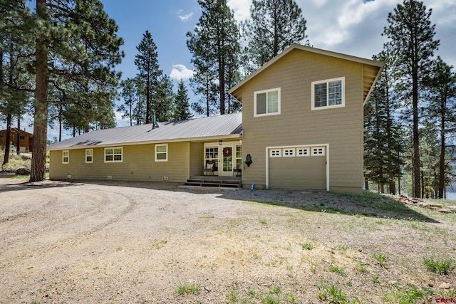 rear view of house with dirt driveway and metal roof