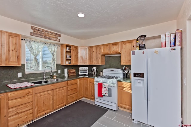 kitchen with white appliances, tasteful backsplash, dark countertops, open shelves, and a sink