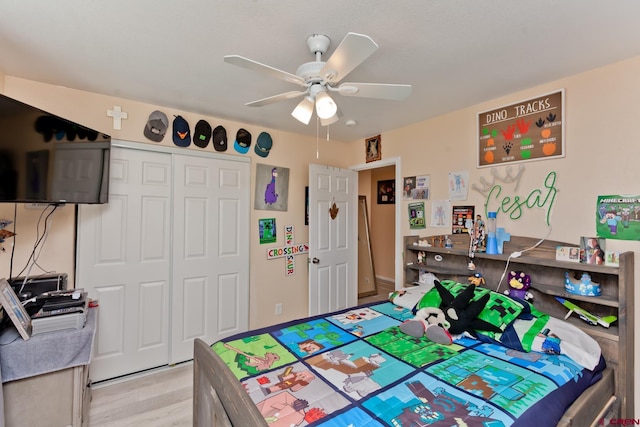 bedroom with light wood-style flooring, a ceiling fan, and a closet