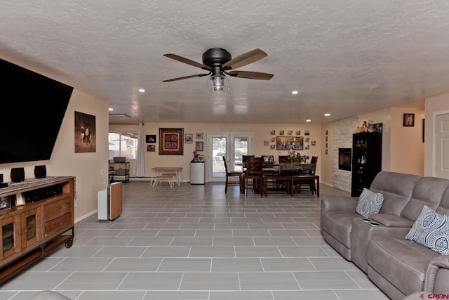 living room featuring recessed lighting, a large fireplace, ceiling fan, and a textured ceiling