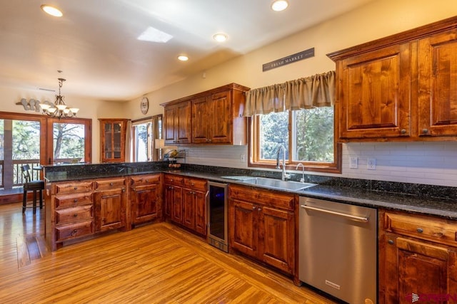 kitchen with a peninsula, stainless steel dishwasher, a sink, and a healthy amount of sunlight