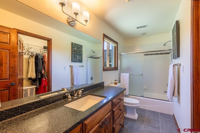 full bath featuring visible vents, toilet, tile patterned floors, combined bath / shower with glass door, and vanity