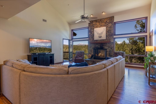 living room featuring ceiling fan, high vaulted ceiling, hardwood / wood-style flooring, a fireplace, and visible vents