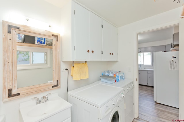 clothes washing area featuring separate washer and dryer, light wood-type flooring, and a sink