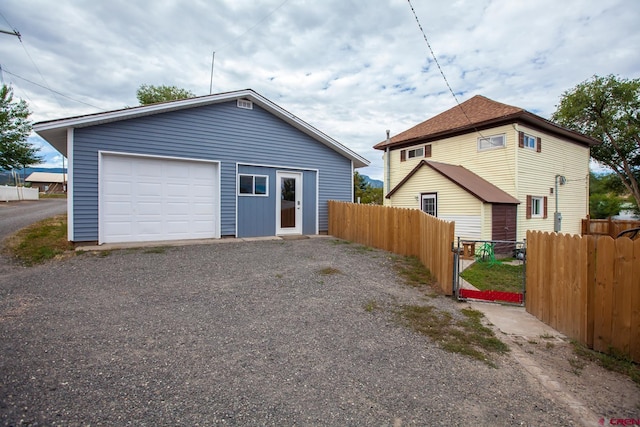 detached garage with gravel driveway and fence