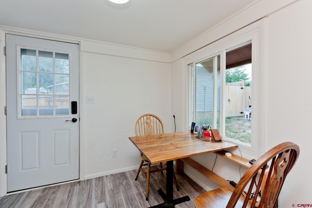 dining room featuring light wood-type flooring, baseboards, and ornamental molding