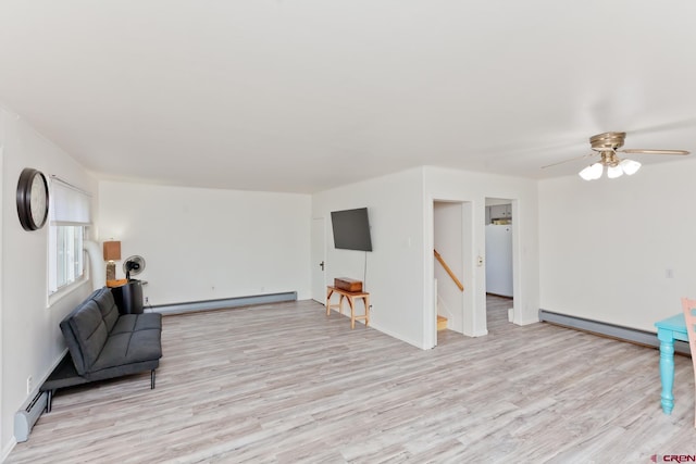 living area with an upstairs landing, light wood-style flooring, and baseboard heating