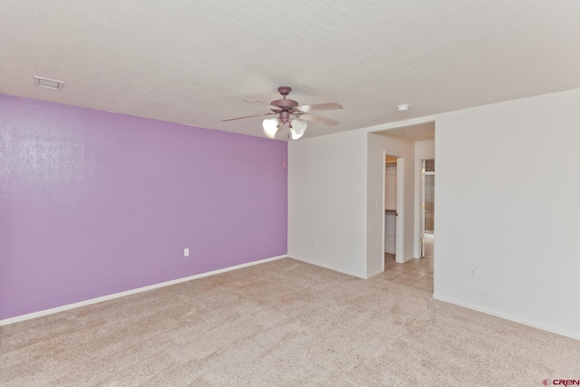 empty room with carpet floors, visible vents, a ceiling fan, a textured ceiling, and baseboards