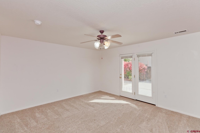 spare room with carpet floors, ceiling fan, visible vents, and baseboards