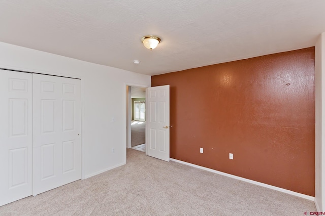 unfurnished bedroom featuring a closet, carpet flooring, a textured ceiling, and baseboards