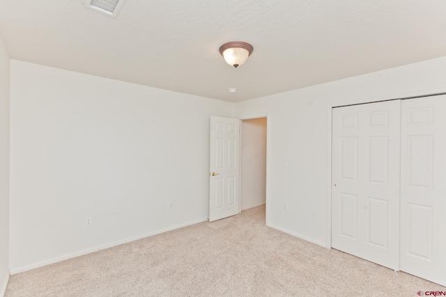 unfurnished bedroom featuring a closet, light carpet, visible vents, and baseboards