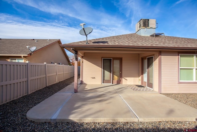 rear view of property featuring central air condition unit, a patio area, fence, and roof with shingles