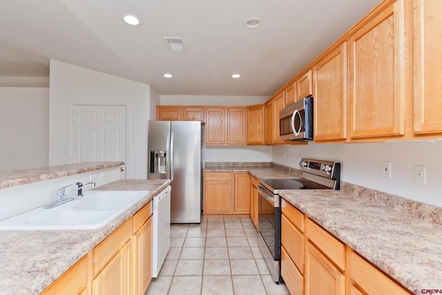 kitchen with appliances with stainless steel finishes, a sink, and light brown cabinetry