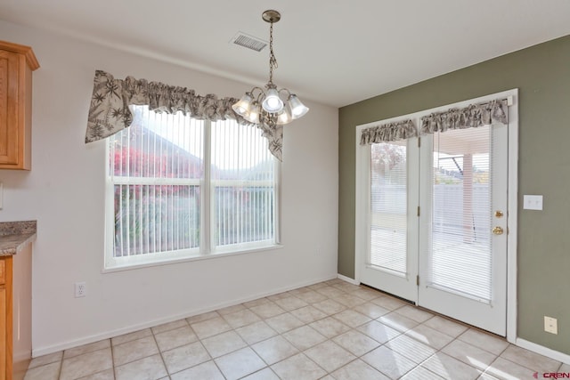 unfurnished dining area with light tile patterned floors, a notable chandelier, visible vents, and baseboards