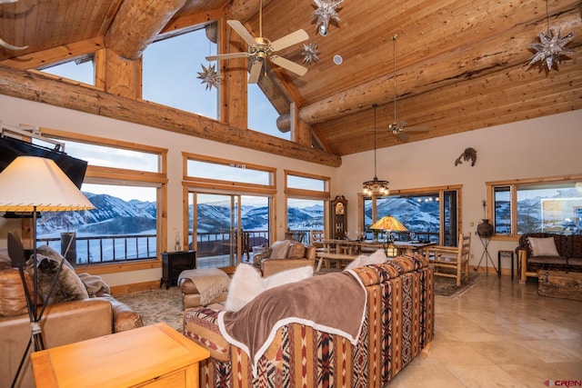 living area featuring a healthy amount of sunlight, wood ceiling, a mountain view, and a ceiling fan