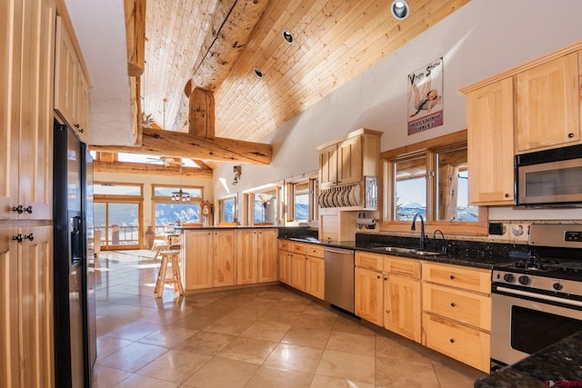 kitchen with stainless steel appliances, light brown cabinetry, a peninsula, and a sink