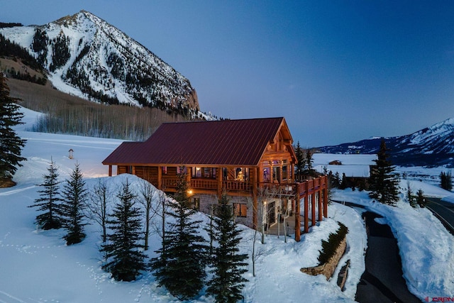 view of snowy exterior featuring metal roof and stone siding