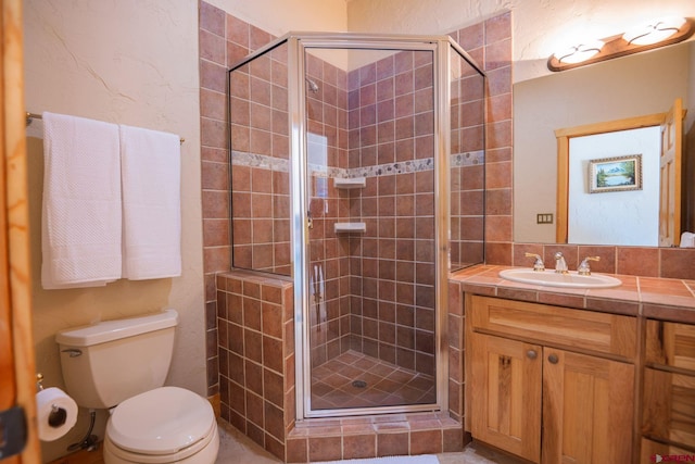 bathroom with toilet, a stall shower, and vanity