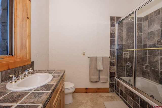 full bath with toilet, tiled shower / bath combo, vanity, and baseboards