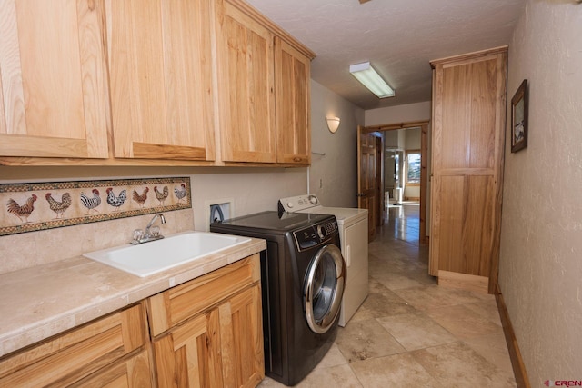 laundry room featuring washing machine and clothes dryer, cabinet space, a textured wall, a sink, and a textured ceiling