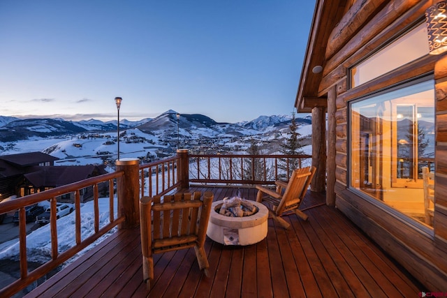 snow covered deck featuring a fire pit and a mountain view