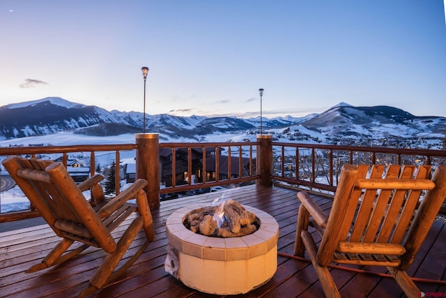 snow covered deck with a fire pit and a mountain view