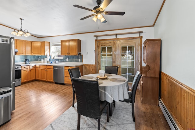 interior space featuring a wainscoted wall, a baseboard heating unit, appliances with stainless steel finishes, and a sink