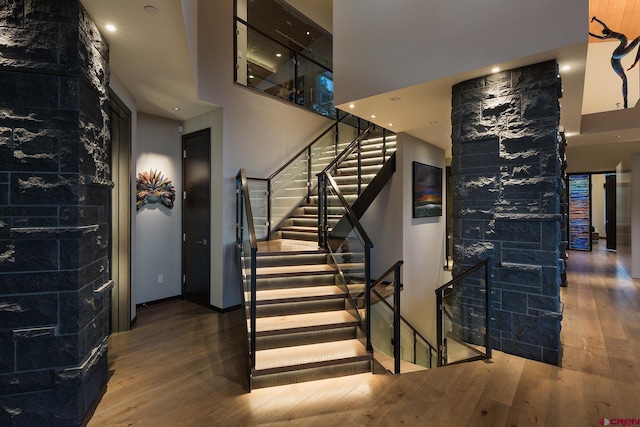 stairs featuring a towering ceiling and hardwood / wood-style flooring